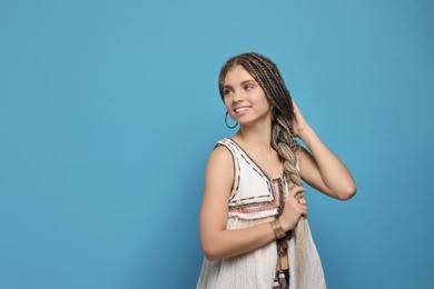 Photo of Beautiful woman with long african braids on blue background, space for text