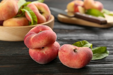 Photo of Fresh ripe donut peaches on black wooden table