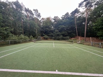 Photo of Tennis court with green grass and net outdoors