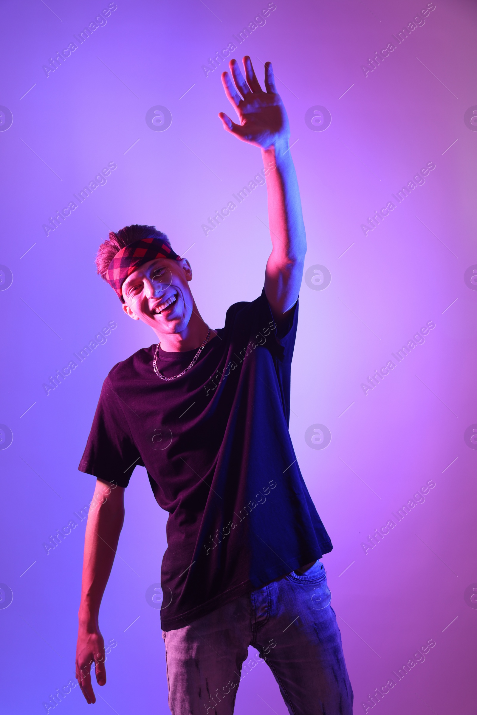 Photo of Stylish young man on color background in neon lights