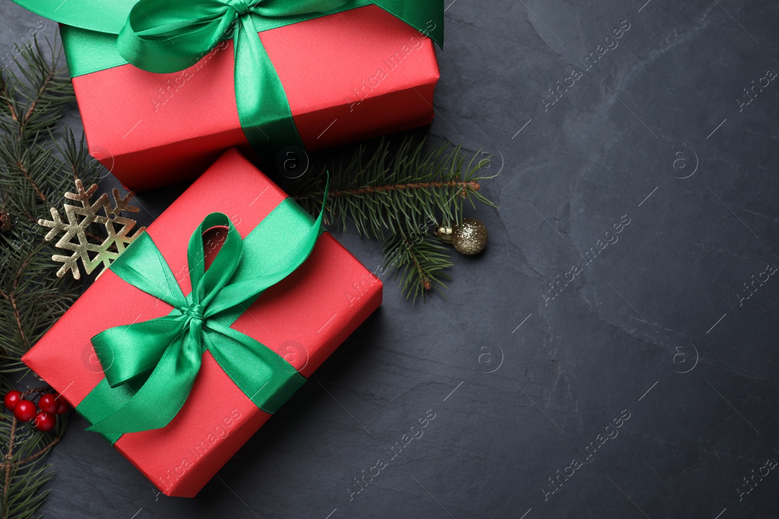 Photo of Flat lay composition with gift boxes and Christmas decorations on dark grey table, space for text