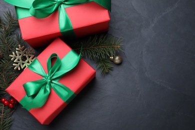 Flat lay composition with gift boxes and Christmas decorations on dark grey table, space for text