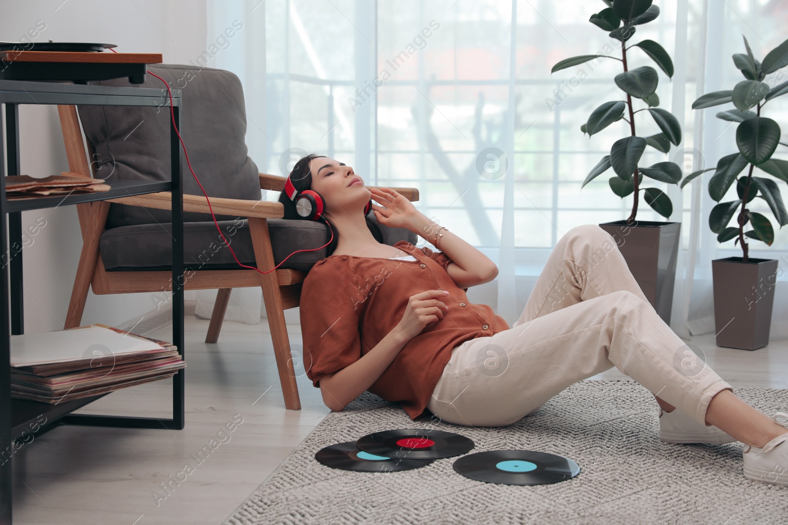 Photo of Woman listening to music with turntable at home