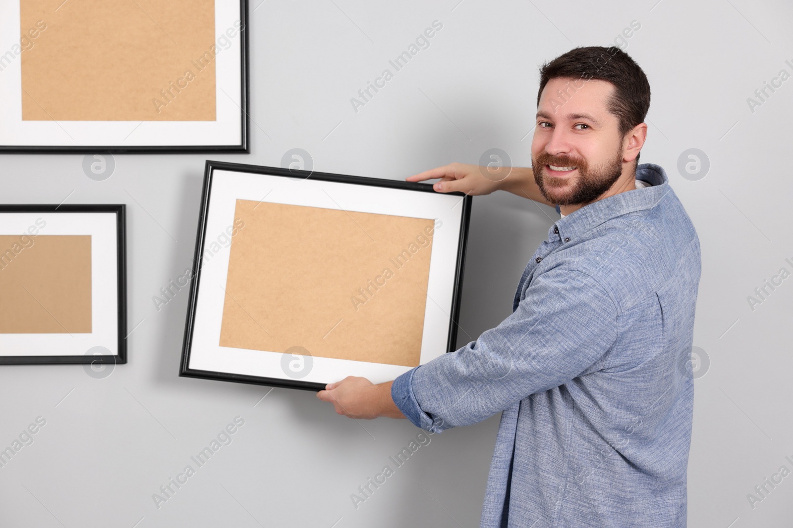 Photo of Man hanging picture frame on gray wall
