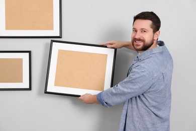 Man hanging picture frame on gray wall