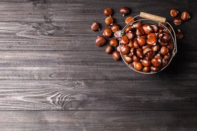 Photo of Fresh sweet edible chestnuts on black wooden  table, flat lay. Space for text