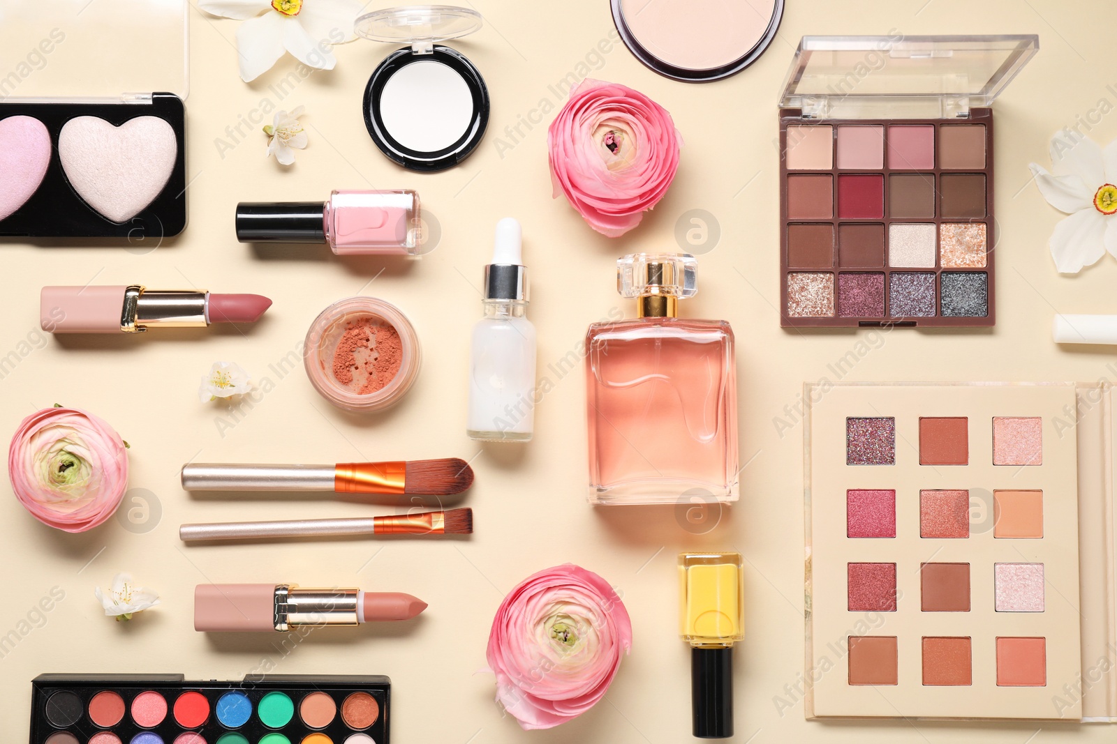 Photo of Flat lay composition with different makeup products and beautiful spring flowers on beige background