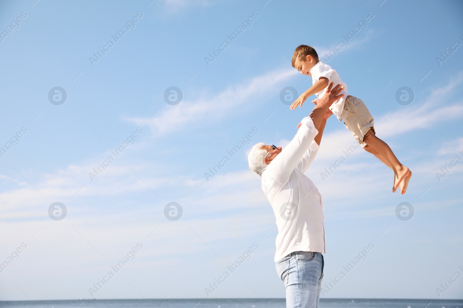 Photo of Cute little boy with grandfather having fun near sea