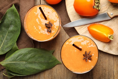 Tasty persimmon smoothie with anise and straws on wooden table, flat lay