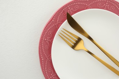 Photo of Stylish setting with cutlery and plates on white textured table, top view. Space for text