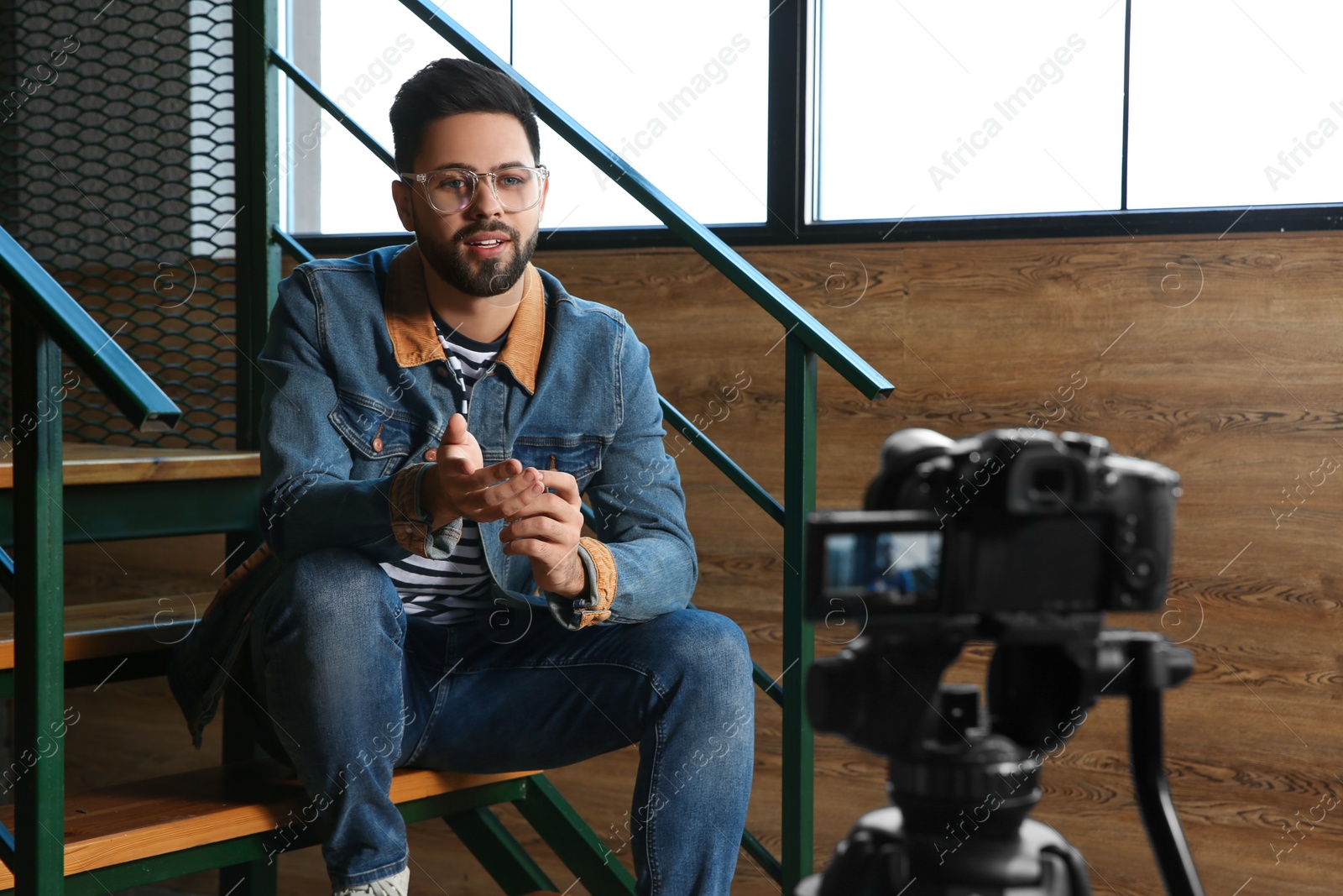 Photo of Young blogger recording video on camera indoors