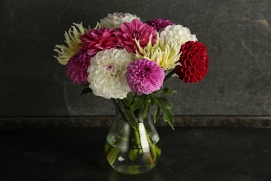 Photo of Bouquet of beautiful Dahlia flowers in vase on black table near grey wall