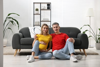 Photo of Young family housing concept. Pregnant woman with her husband on floor at home