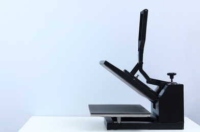 Photo of Heat press machine on table against light background, space for text