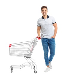 Young man with empty shopping cart on white background