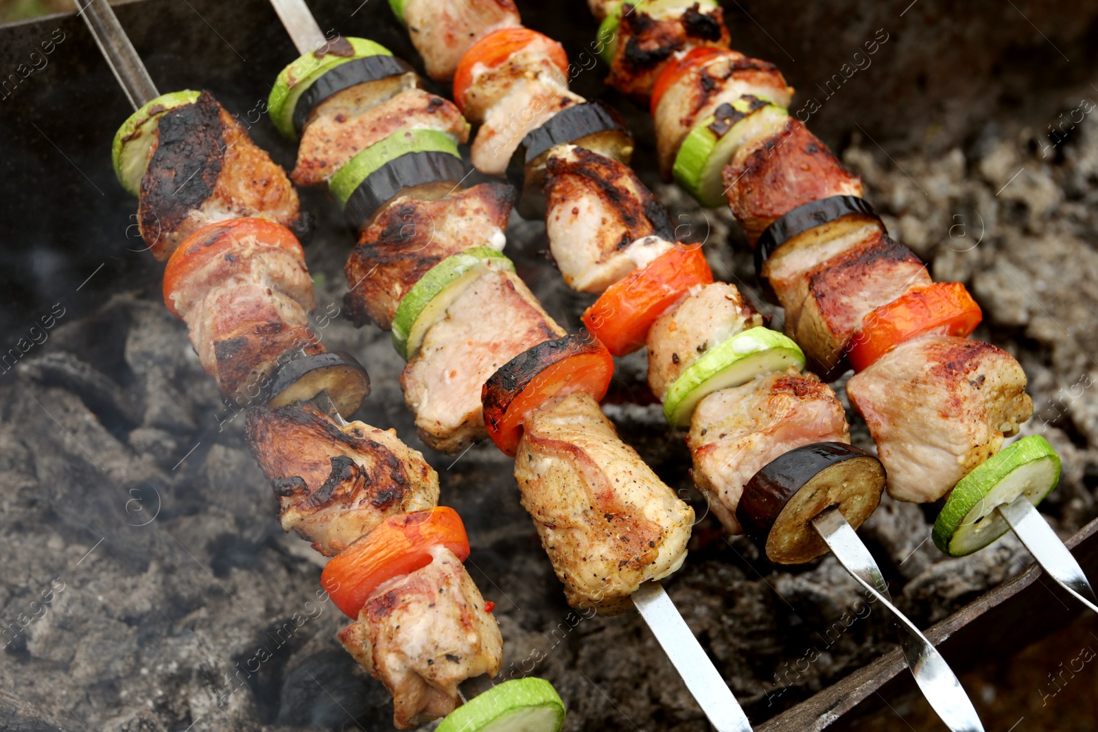 Photo of Cooking meat and vegetables on brazier, closeup