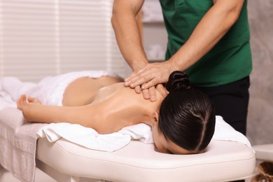 Photo of Woman receiving professional neck massage on couch in spa salon