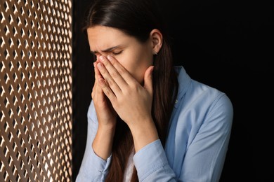 Photo of Upset woman listening to priest during confession in booth