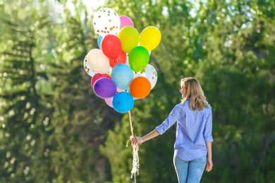 Photo of Young woman with colorful balloons in park on sunny day