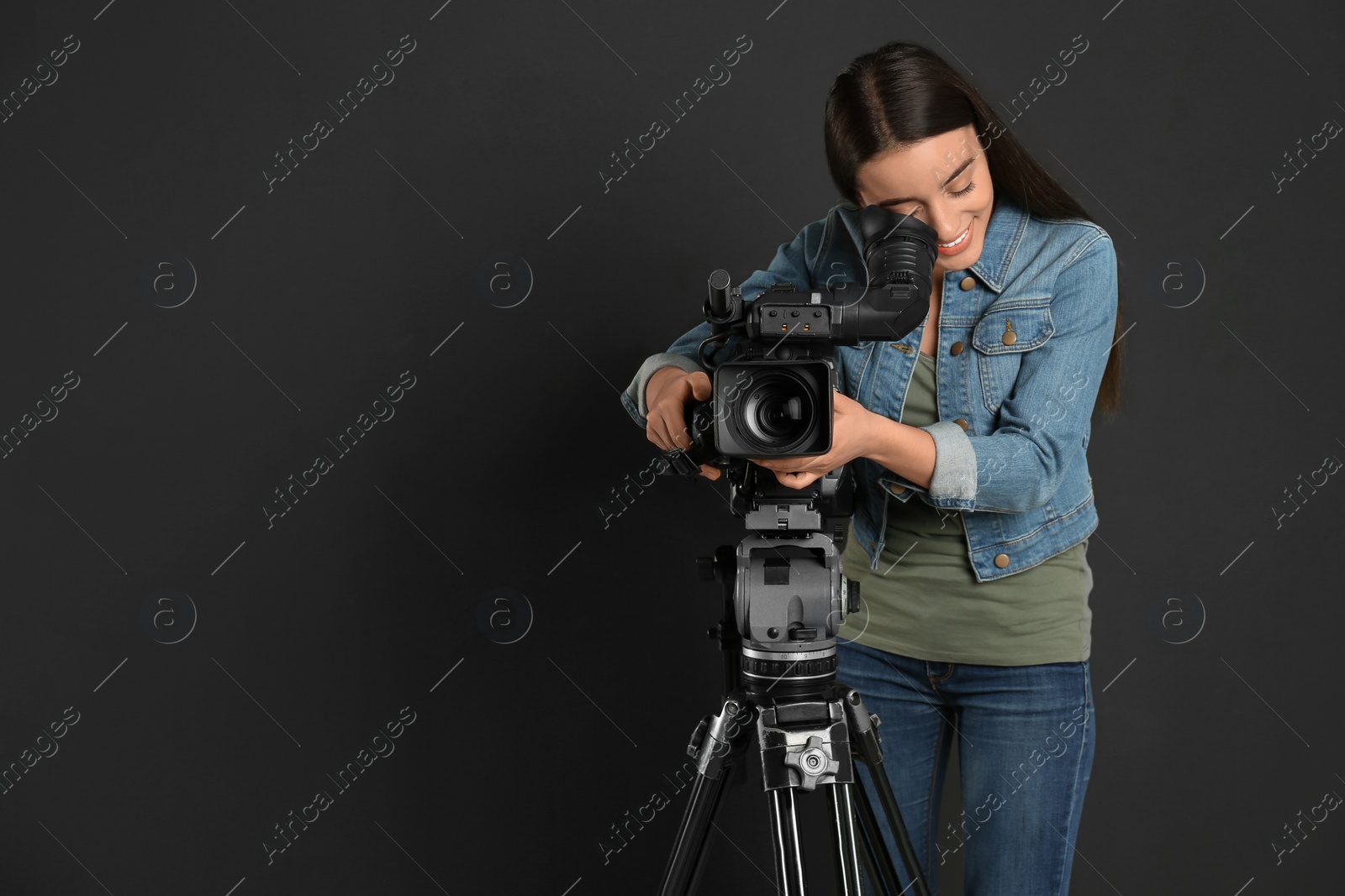 Photo of Operator with professional video camera on black background, space for text