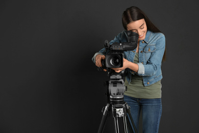 Photo of Operator with professional video camera on black background, space for text