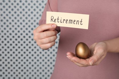 Photo of Woman holding golden egg and card with word retirement on light background, closeup. Pension concept