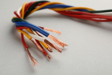 Photo of Many twisted electrical wires on light background, closeup