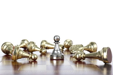 Photo of Silver pawn among fallen golden chess pieces on wooden board against white background