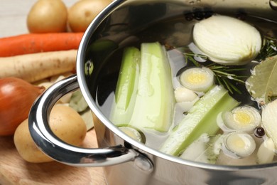 Pot and different ingredients for cooking tasty bouillon on table, closeup