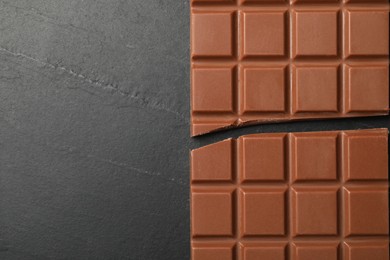 Photo of Tasty broken chocolate bar on grey table, top view. Space for text