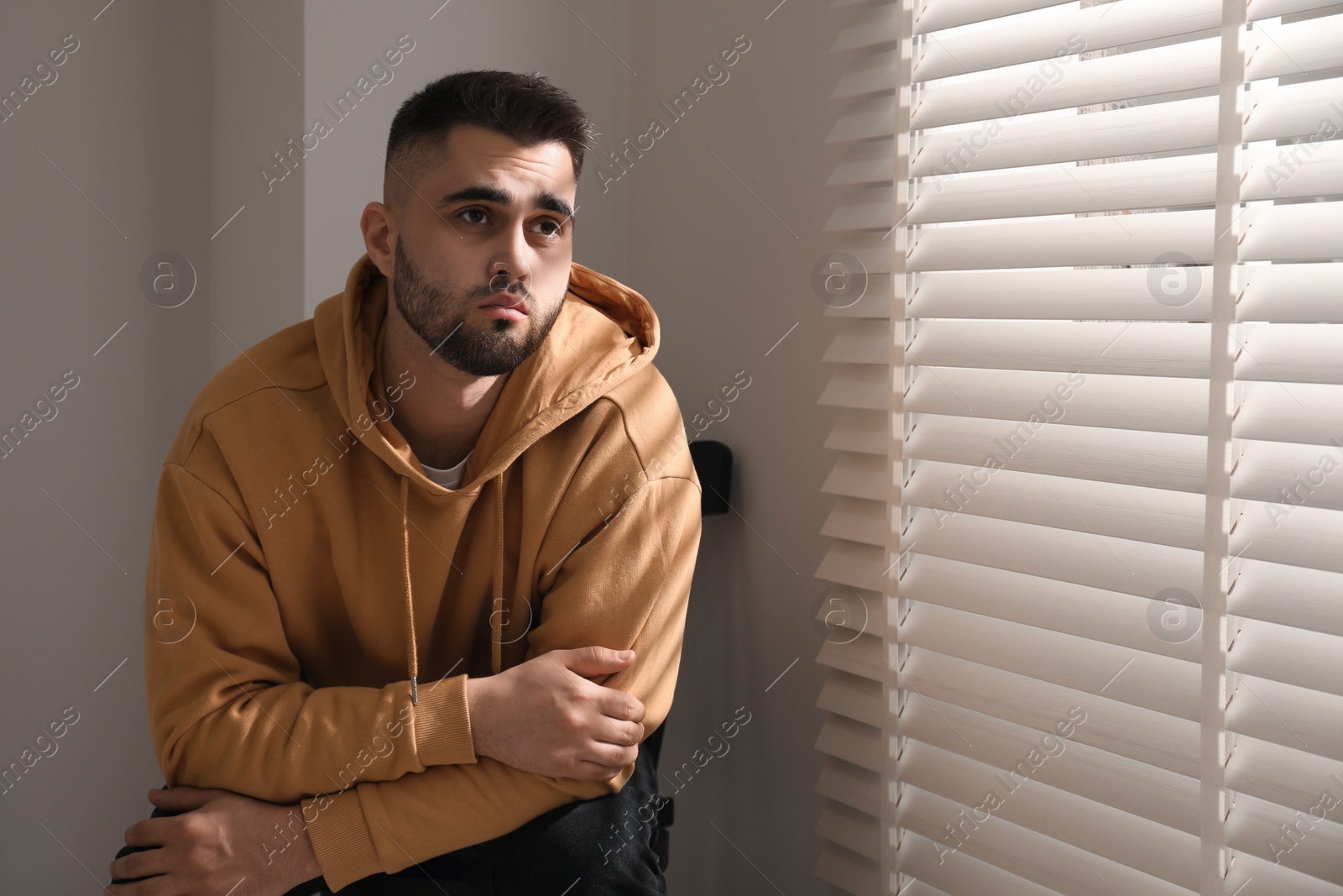 Photo of Sad man sitting on chair near window