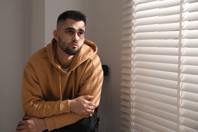 Sad man sitting on chair near window