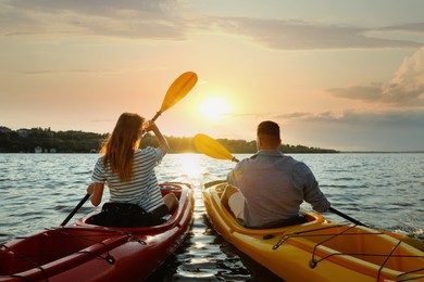Photo of Couple kayaking on river at sunset, back view. Summer activity