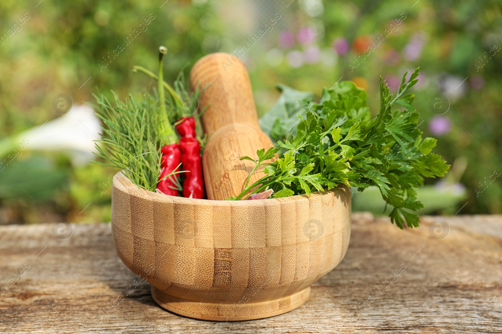 Photo of Mortar with pestle and different ingredients on wooden table outdoors