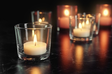 Photo of Burning candle on table in darkness, space for text. Funeral symbol