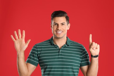 Photo of Man showing number six with his hands on red background