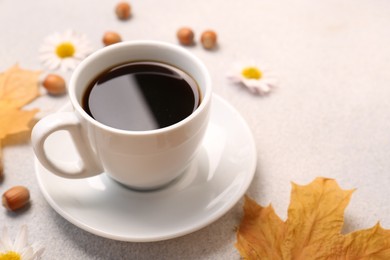 Composition with cup of hot drink and autumn leaves on light grey textured table, closeup