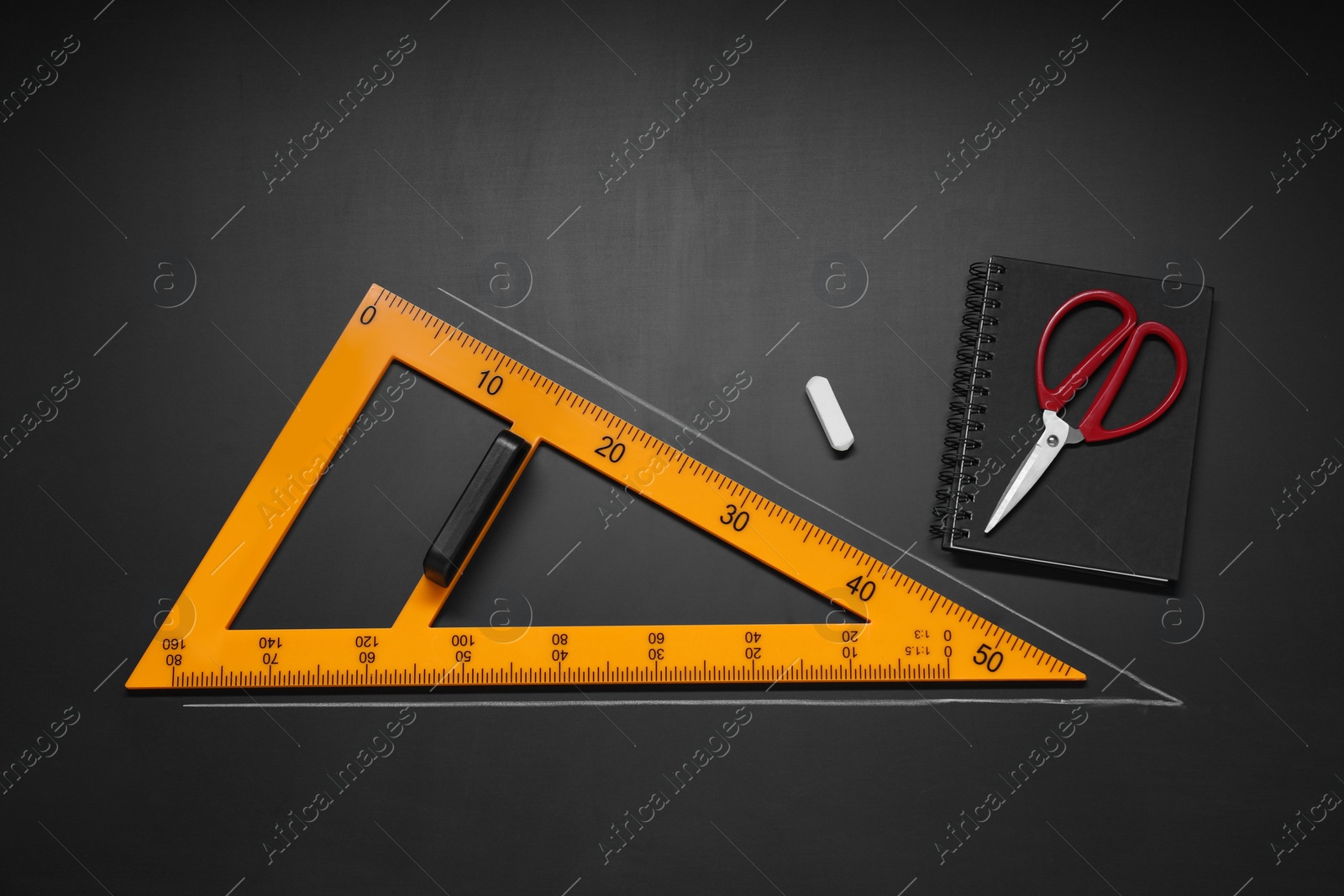 Photo of Flat lay composition with triangle and chalk, on blackboard