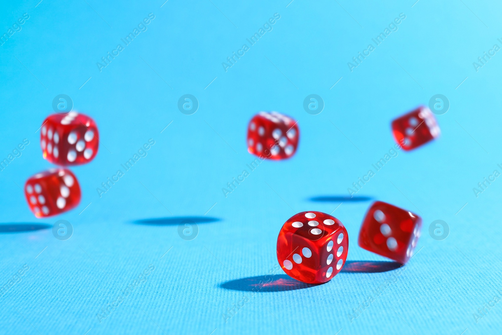 Photo of Many red game dices falling on light blue background