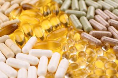 Many different vitamin capsules on yellow background, closeup