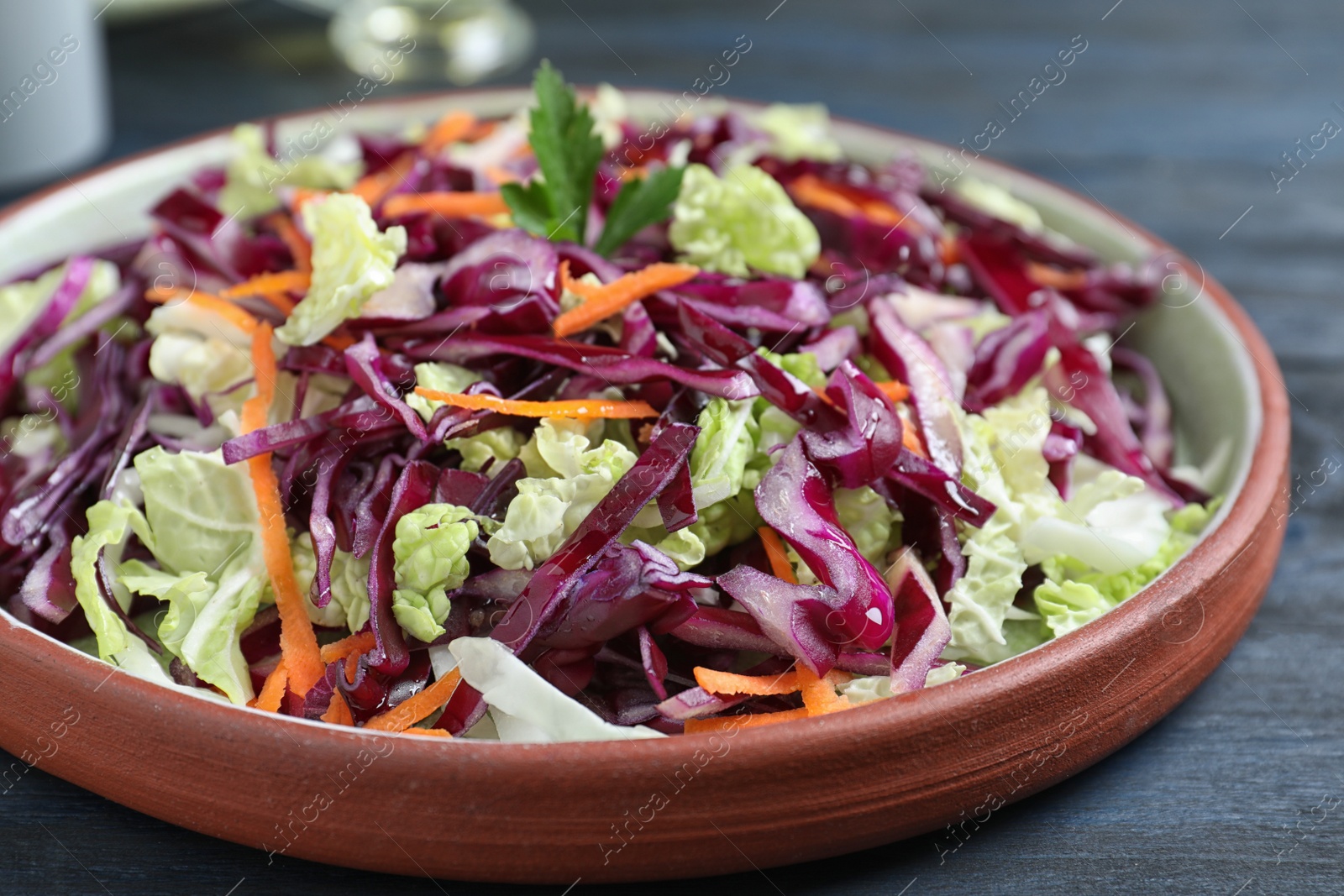 Photo of Fresh cabbage salad served on blue wooden table, closeup