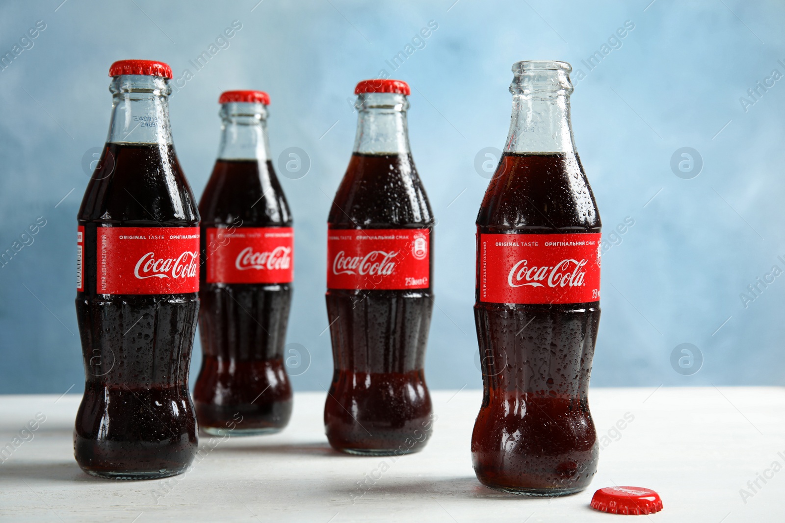 Photo of MYKOLAIV, UKRAINE - NOVEMBER 15, 2018: Bottles of Coca Cola on table against color background