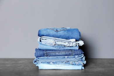 Photo of Stack of different jeans on table against gray background