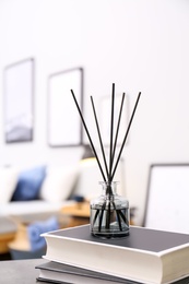 Aromatic reed air freshener and books on table in room