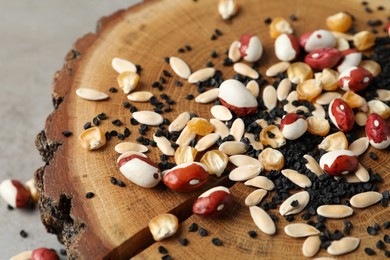 Mixed vegetable seeds on wooden log, closeup