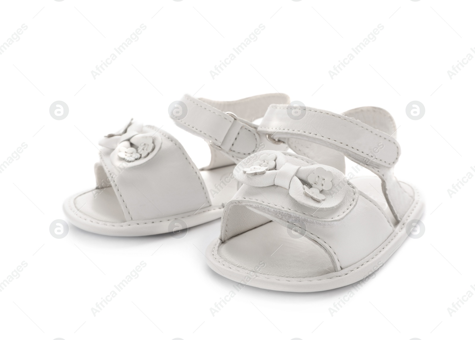 Photo of Pair of cute baby sandals decorated with bows on white background