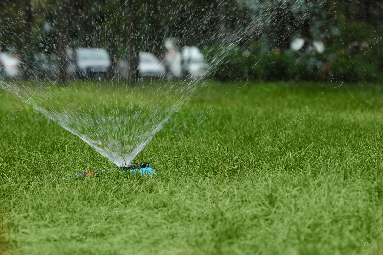 Photo of Automatic sprinkler watering green grass in park. Irrigation system