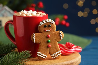 Photo of Tasty gingerbread man cookie and cocoa with marshmallows on blue wooden table, closeup