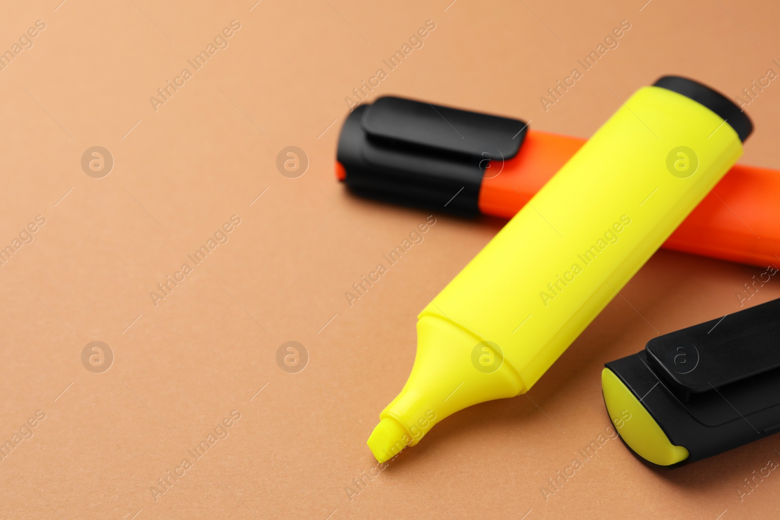 Photo of Bright color markers on pale orange background, closeup. Space for text