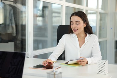 Happy woman using tablet at white desk in office, space for text